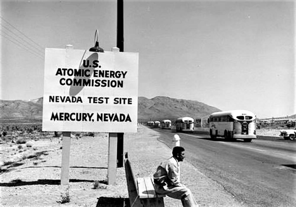 Man sitting near a Nevada Test Site sign, Nevada, United States, 1955 From 1951–1962.