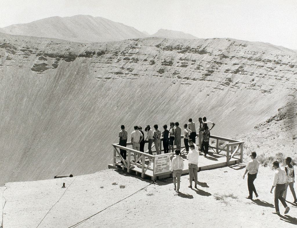 People stand at the edge of a gigantic crater created by the Project Sedan nuclear test explosion, 1950s.