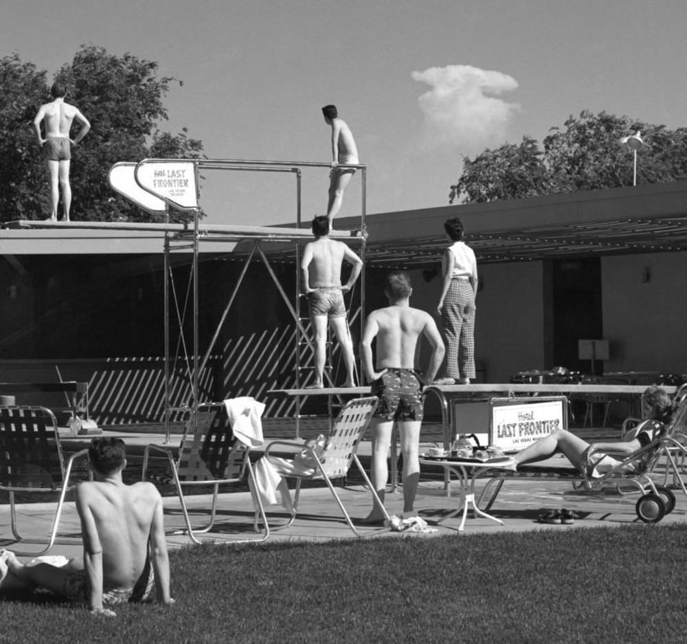 Early morning bathers at a hotel pool in Las Vegas stop to watch the mushroom cloud of an atomic detonation at a test site about 75 miles from the city. May 8, 1953.
