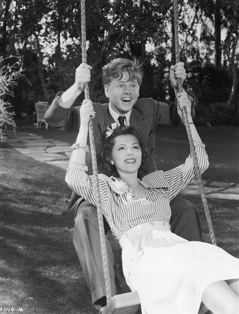 Mickey Rooney with Ann Rutherford smile as they share a swing together, 1939.