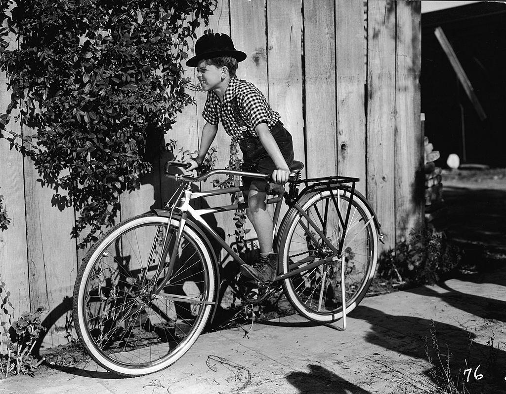 Mickey Rooney ina bowler hat on a bicycle in a film still from one of the numerous 'Mickey McGuire' comedy shorts, 1930.