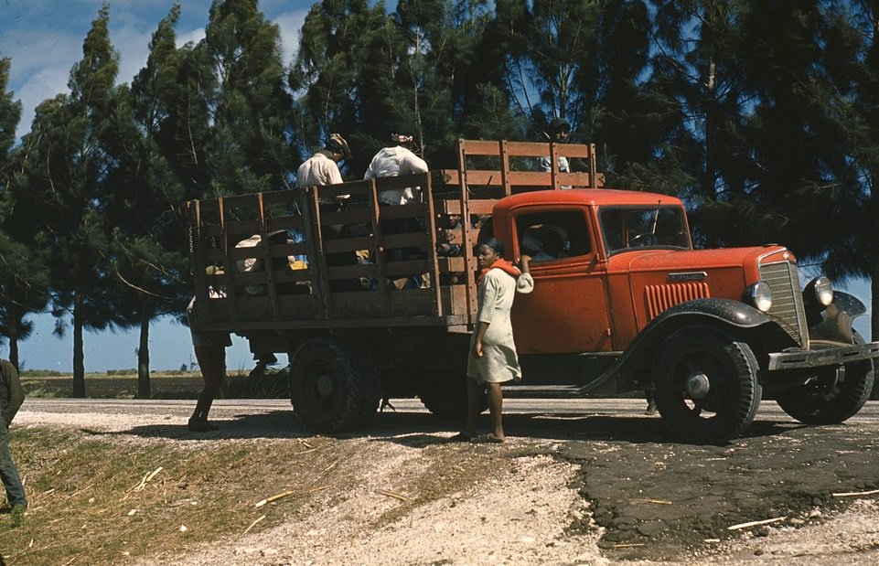 Photograph shows a 1934-1936 International C30 truck transporting people who might be farm workers.