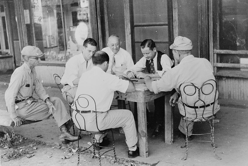 Playing dominoes or cards in front of drug store in center of town in Mississippi Delta, 1939.