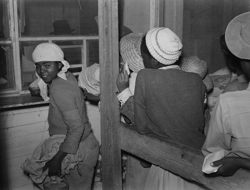 Day laborers brought in truck from nearby towns, waiting to be paid off for cotton picking and buy supplies inside plantation store on Friday night, Mississippi Delta. November 1939