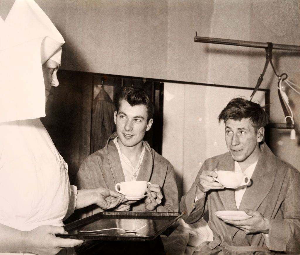 A ward sister serves mugs of soup to Manchester United survivors Kenny Morgans (left) and Bobby Charlton following the Munich Air Disaster