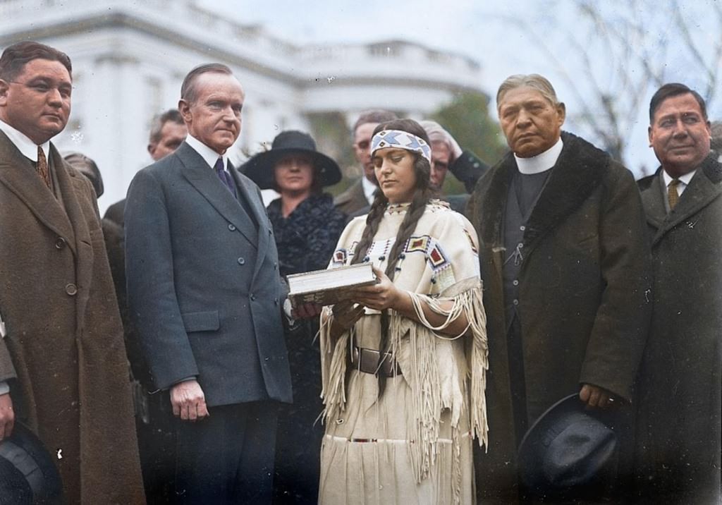 This Native American woman, center is meeting US President Calvin Coolidge in 1923 in advance of the Indian Citizenship Act.