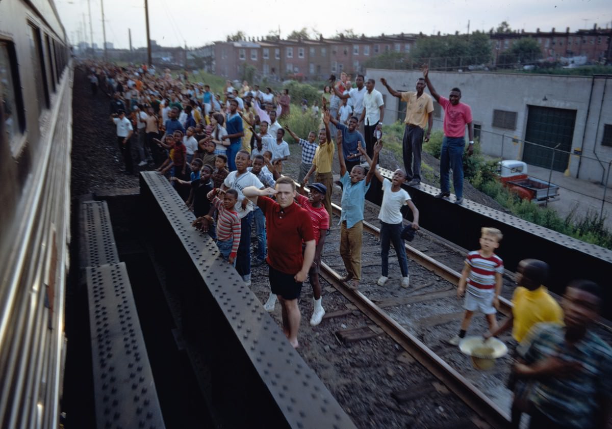 People wave and salute as Robert F. Kennedy’s funeral train travels past, rolling from New York City to Washington, D.C., on June 8, 1968