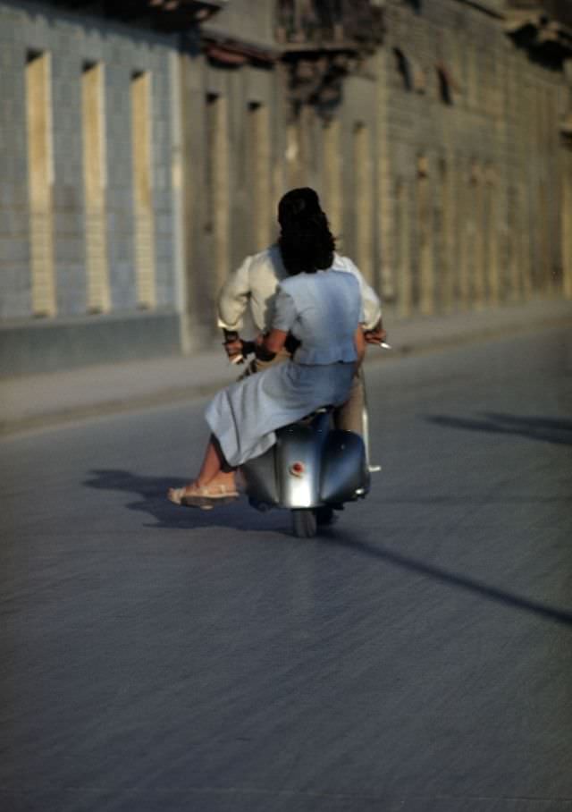 A couple ride a Vespa.