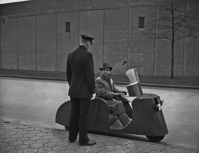 A man sitting on a three-wheeled 'Motorette' scooter.