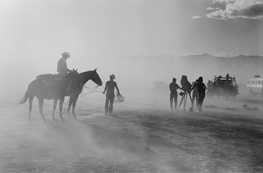 A man riding a horse while a camera is set up for a scene in 'The Misfits', filming on location in the Nevada Desert.