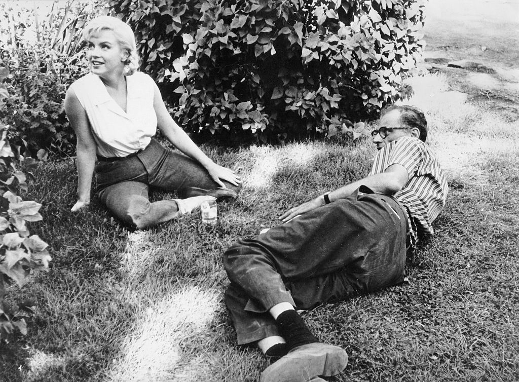 Marilyn Monroe with her husband Arthur Miller, sitting on a meadow during a break in filming 'The Misfits'