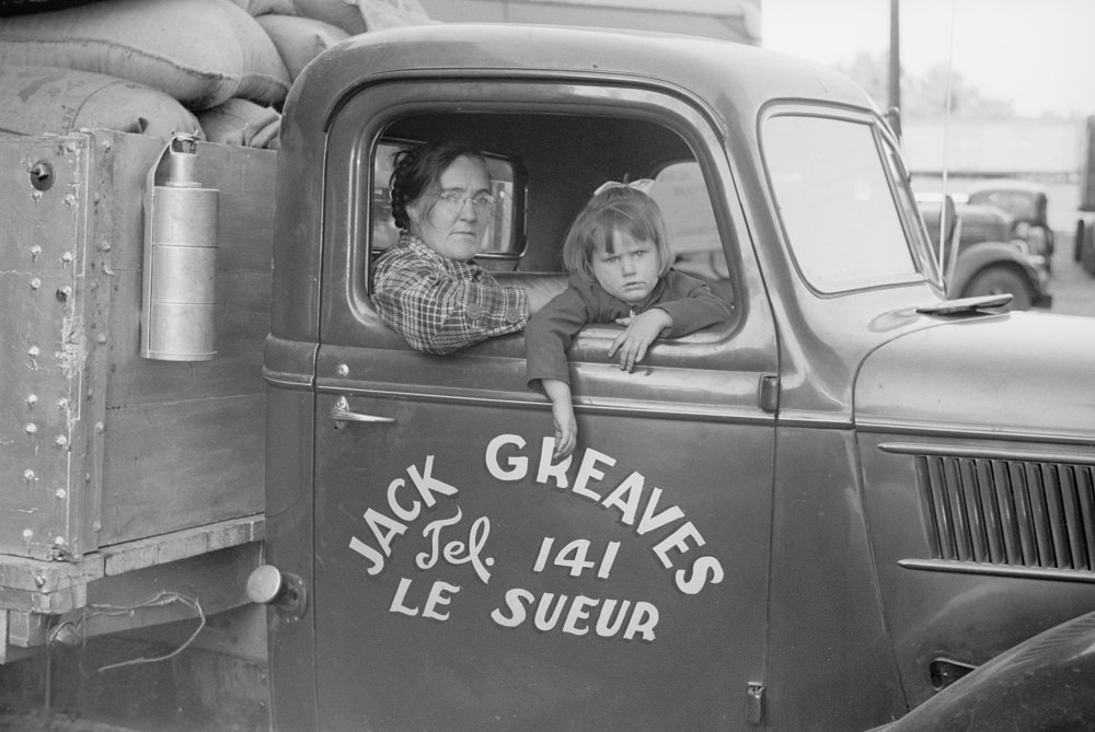 Family of trucker waiting while truck is being loaded, Minneapolis, 1930s.