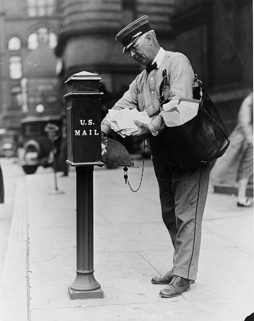 Postal carrier Albert S. Dilley empties a mailbox on his downtown route. Minneapolis, Minnesota, 1930.