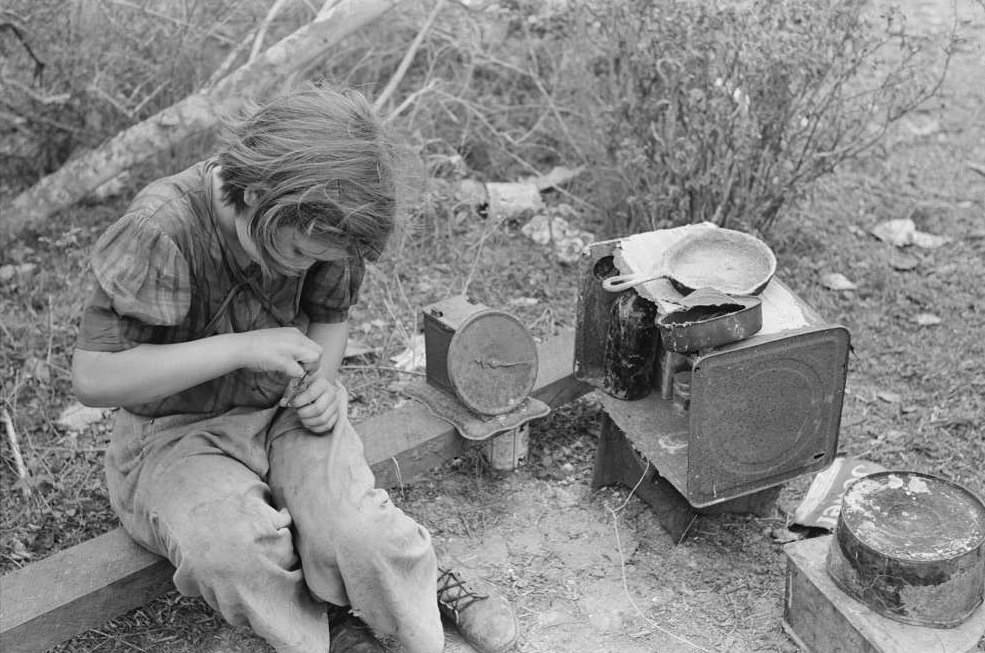 A child of white migrant in her playhouse. The rusted scales represented a clock to the little girl. Near Harlingen, Texas.