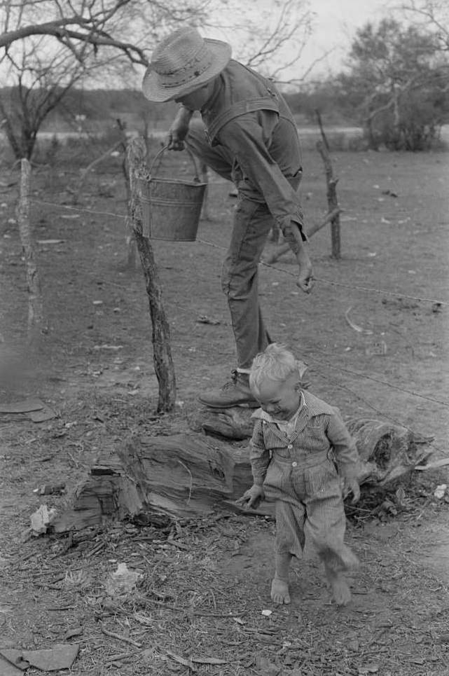 Child of white migrant climbing fence with pail of water near Harlingen, Texas.