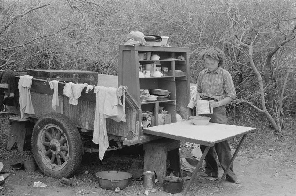 Two-wheeled trailer with kitchen cabinet fitted on the end. This is copied from the old chuck wagons. Harlingen, Texas migrant camp.