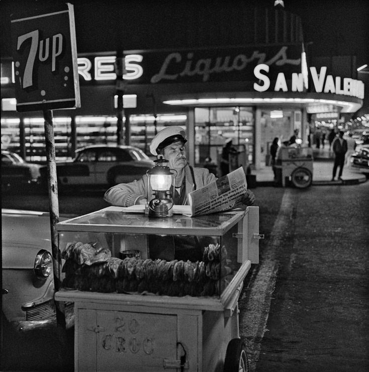 Taco vendor in Tijuana, Mexico, catching up on the day’s news until the next customer shows up, 1964