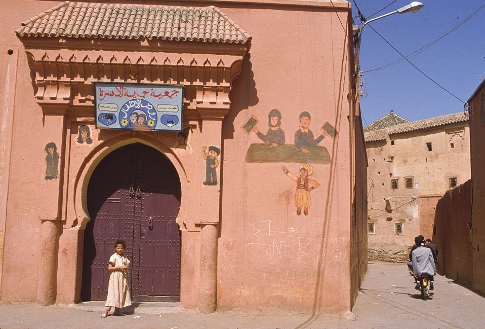 A girl stands outside a building in a street in Marakesh, Morocco.