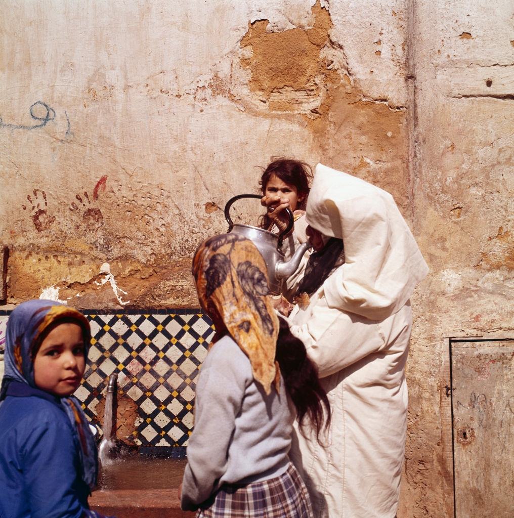 Woman with girl at water point in Morocco, 1960.