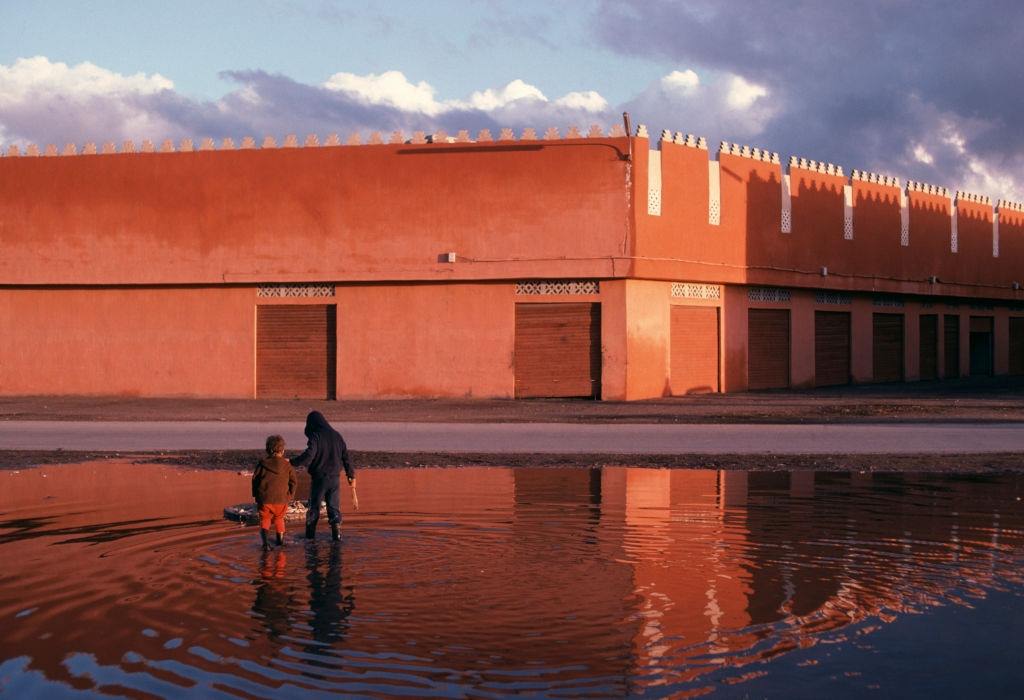 Children wading through a puddle in a street in Marrakech, February 1979, Morocco.