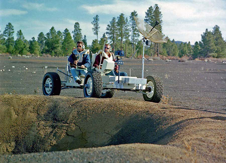 The astronauts Jim Irwin and Dave Scott pilot Grover near the rim of a large crater in the Cinder Lake Crater Field.