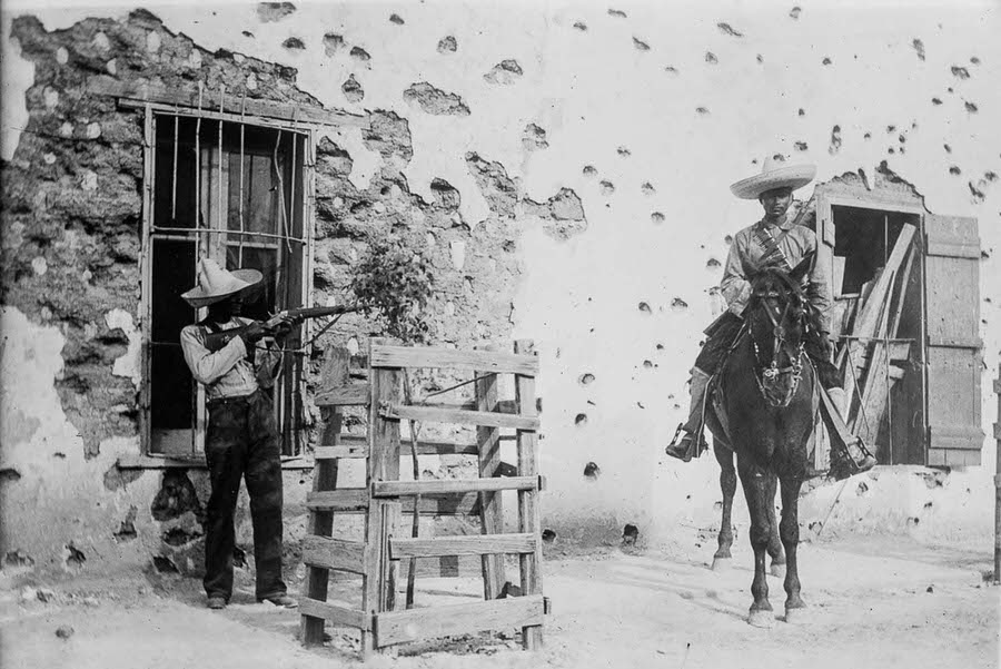 Rebels in front of an adobe house riddled with bullet holes in Ciudad Juarez.