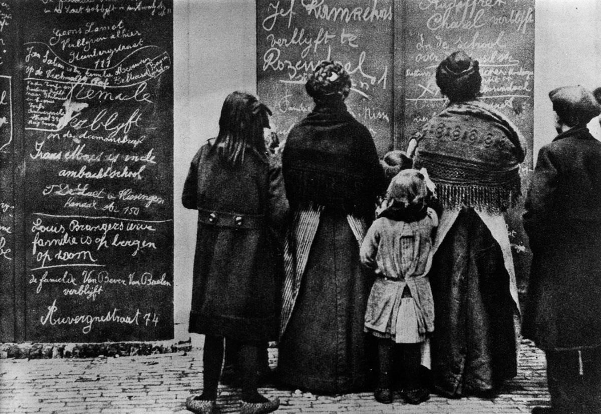 Belgian refugees read Flemish messages left by other refugees in a French town, 1915.
