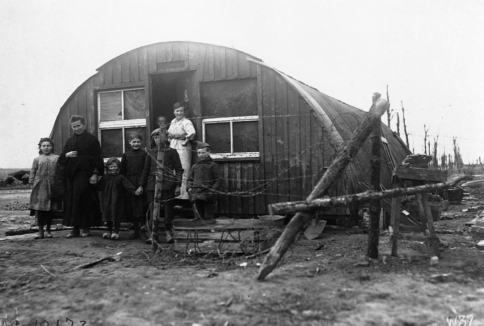 Belgian refugee family stands outside the abandoned British field hut they moved into after the armistice ended World War I.