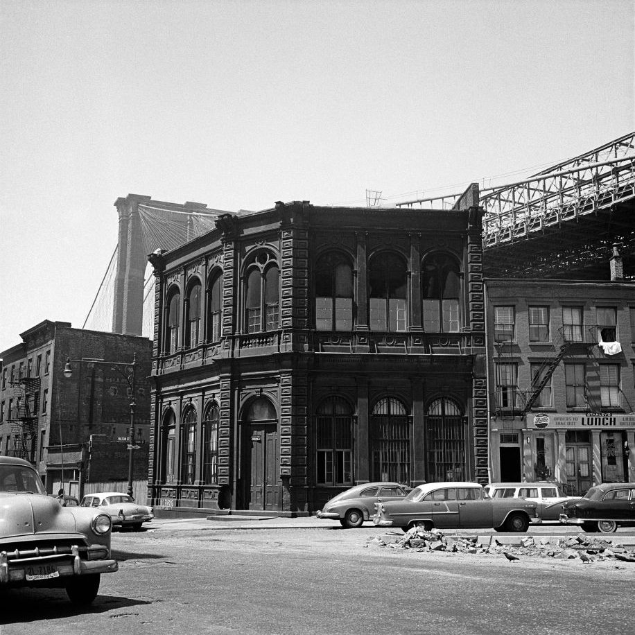 The corner of Fulton and Front Streets, including the diner Stanley's Lunch, with the Brooklyn Bridge in the background, March 1958.