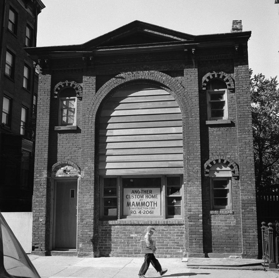 A boy carrying a newspaper walks by a carriage house, at 31 Pineapple Street, built in the 1880s to serve as a stable for the Brooklyn Fire Department in Brooklyn Heights, March 1958.