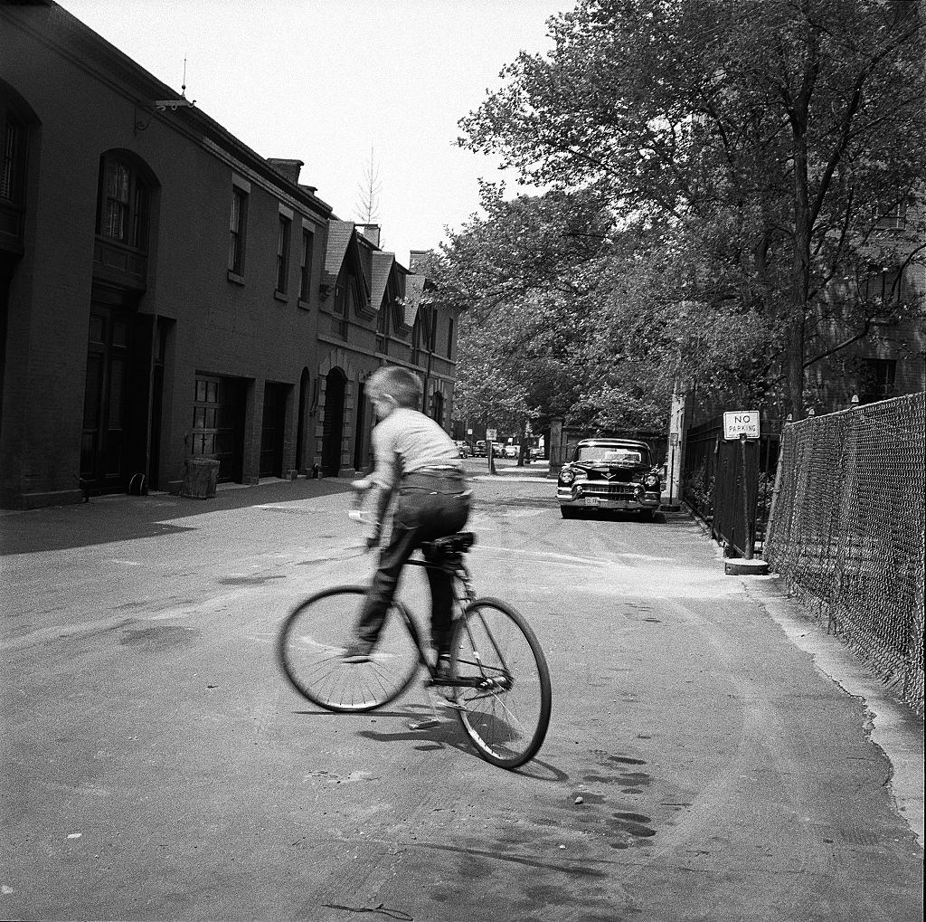 A young boy rides his bicycle in the street in Brooklyn Heights, March 1958.
