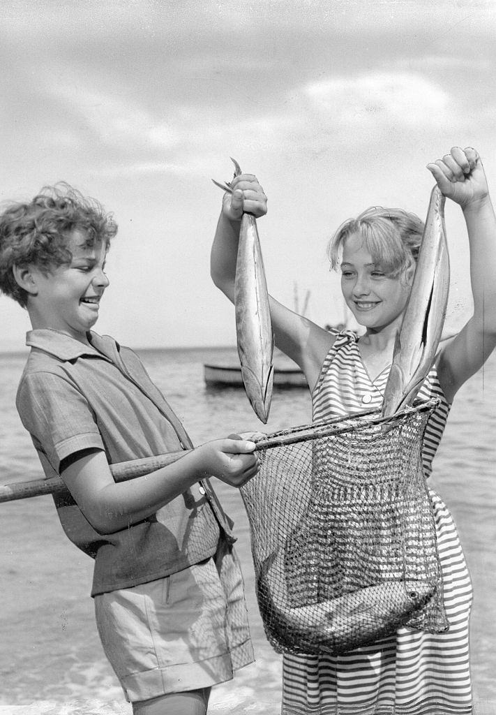 Christine Kaufmann holding two fishes, 1956.
