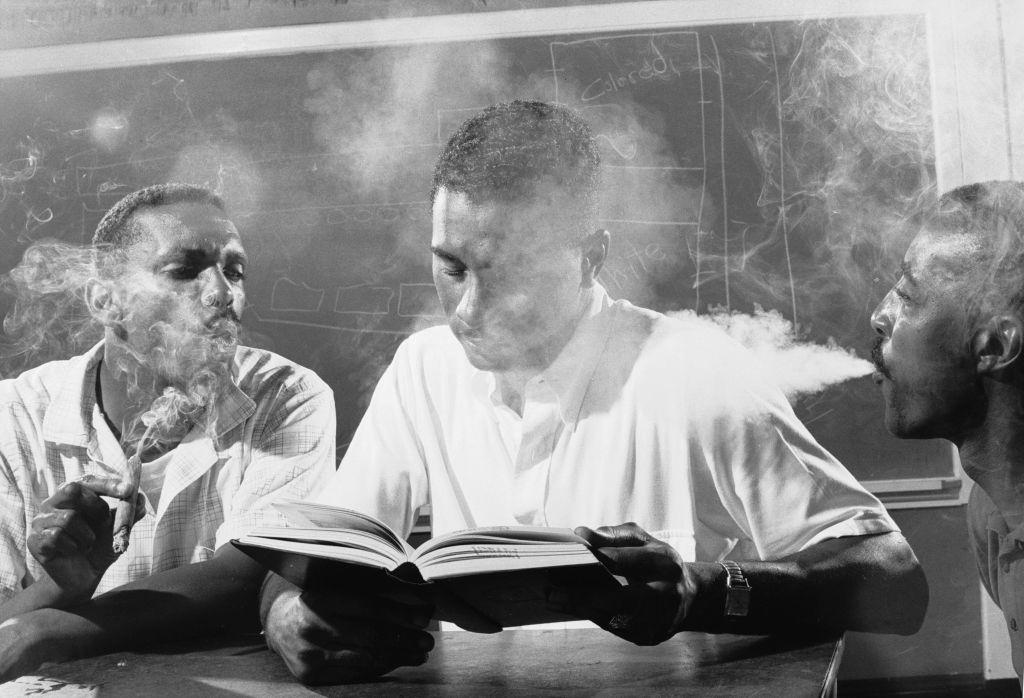 Leroy Hill (left) and another man blow smoke into the face of an unidentified volunteer, 1960.