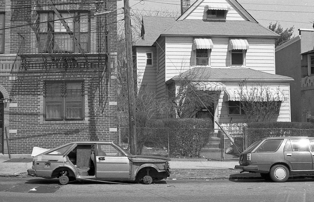 A vehicle that has been stripped of it's tires, and other parts on 36th Avenue (near 108th Street), in the Corona neighborhood. Queens, New York, 1990.