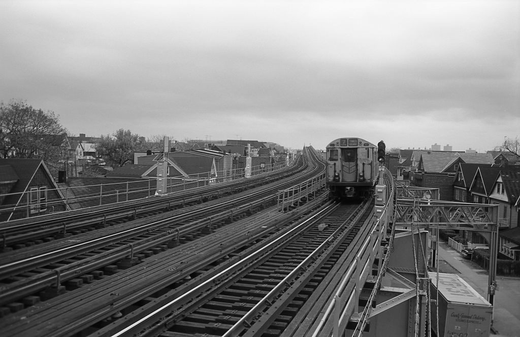 The number Seven Train travels along the elevated subway tracks through a residential neighborhood in Corona, Queens, 1974.