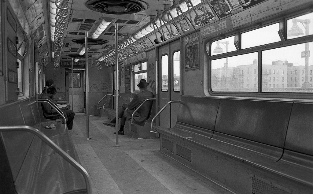 Three commuters sit in a graffiti covered subway car as it travels through Corona, Queens, 1974.