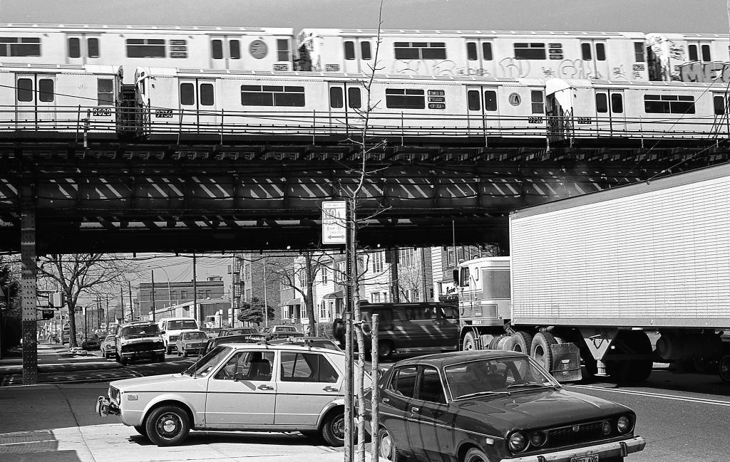 Street traffic under the elevated subway tracks at the intersection of 108th Street and Roosevelt Avenue in Corona. Queens, New York, 1982.