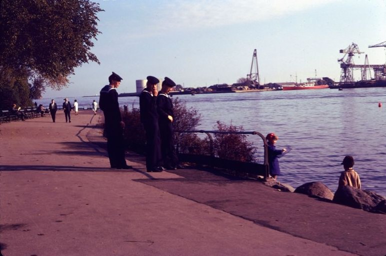 Little girl sketching the Little Mermaid, observed by some passing sailors, Copenhagen, Denmark