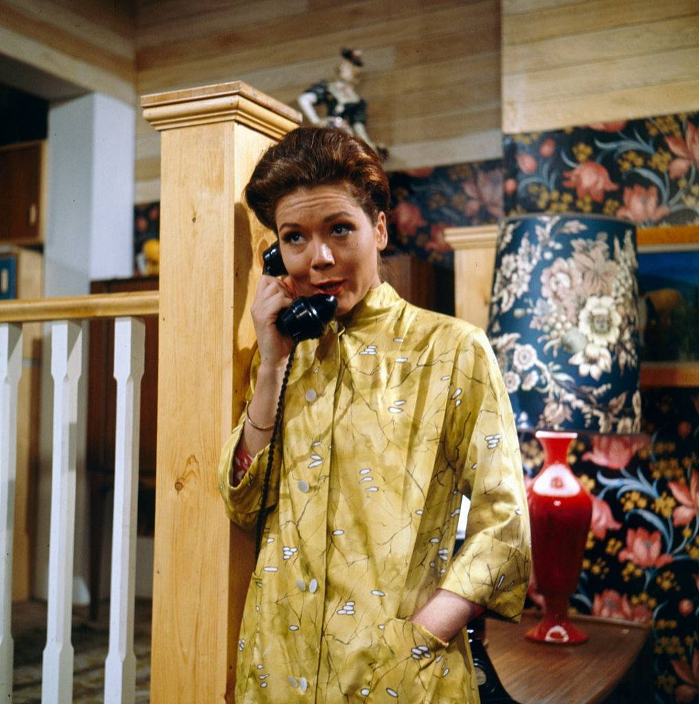 Diana Rigg pictured holding a telephone receiver in a scene from the television drama 'The Hot House' in 1964.