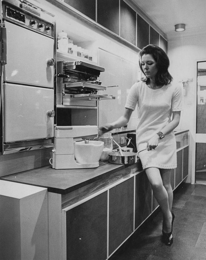 Diana Rigg trying out a new cook'n dining room ' in the electric pavilion at the Daily Mail Ideal Home Exhibition, 1967.