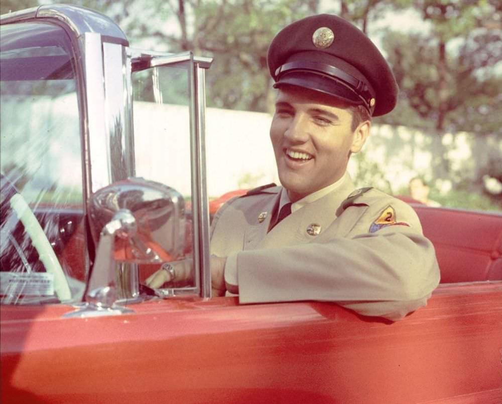 Elvis sits behind the wheel of a red car, returning home for two weeks after basic training in June of 1958.