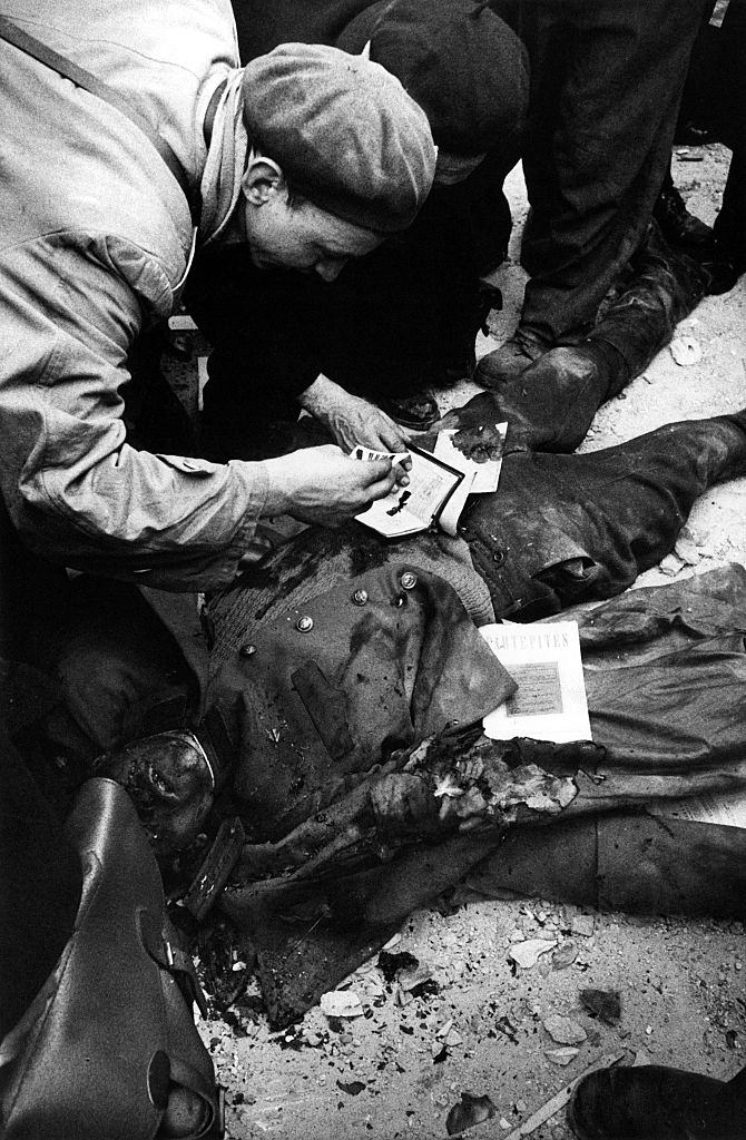 Some insurgents leafing through the documents found on the body of an agent of the Hungarian secret police (AVH). Budapest, November 1956