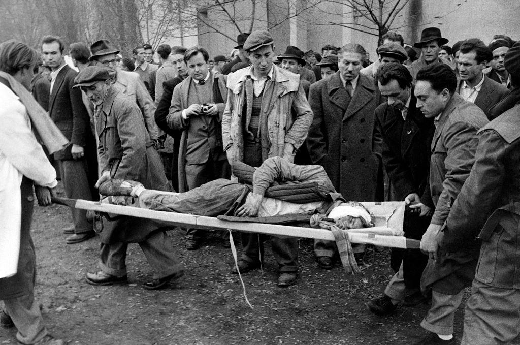 A patriot, wounded during the battle for the headquarters of the Communist Party, is transported on a stretcher to the improvised aid stations. Budapest, November 1956