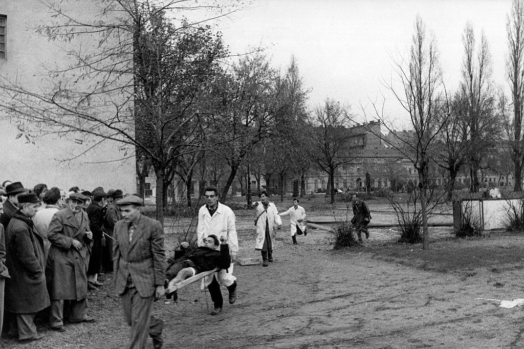 A wounded man is led to safety during the revolt. Budapest, November 1956