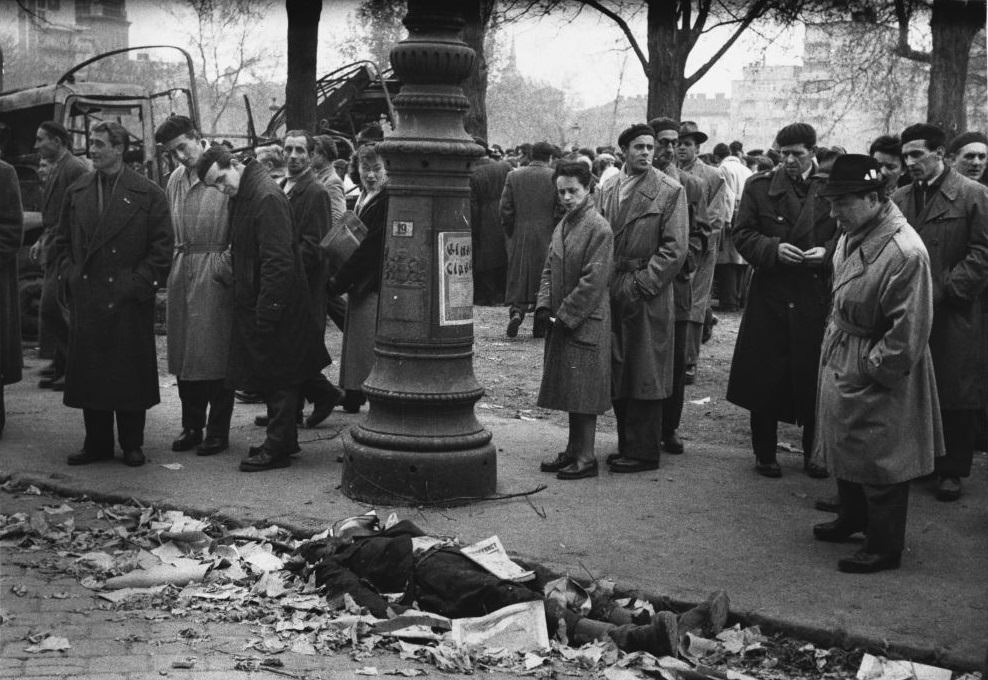 Hungarians stare at the remains of a man from the secret police, the A.V.H. during the 1956 revolution.