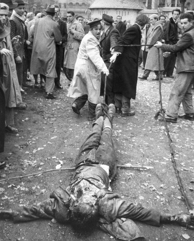 A beaten Hungarian colonel in the AVO, the secret police of the communist regime, is dragged along the ground by ropes attached to his ankles by angry protesters.