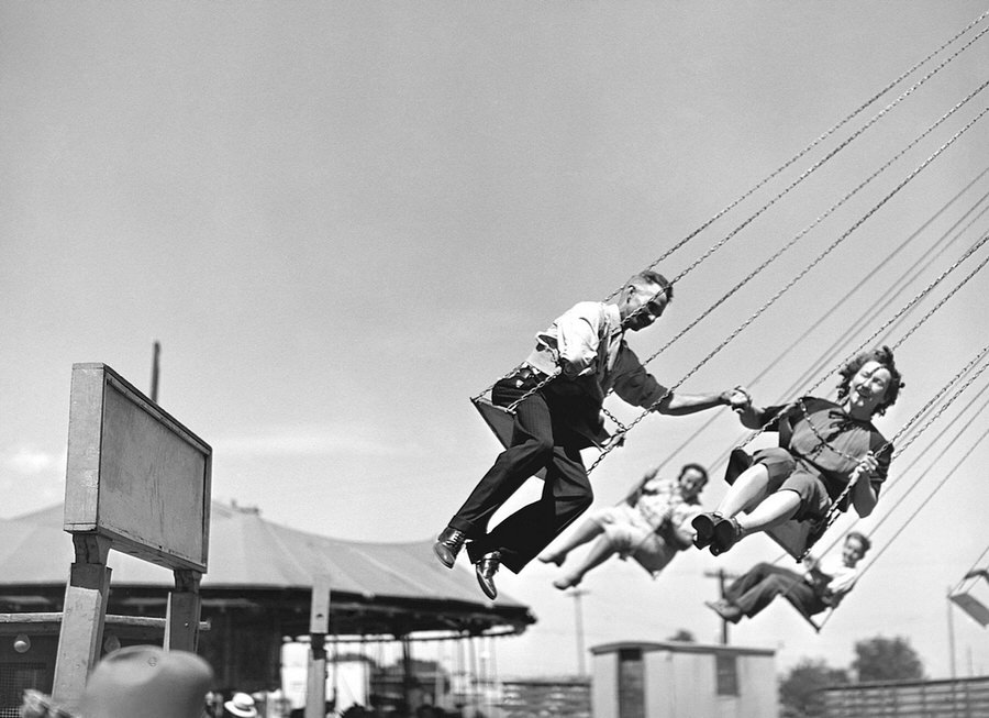 A couple hold hands as they spin around an amusement park ride on the midway, in Vale, Oregon, on the Fourth of July, 1941.