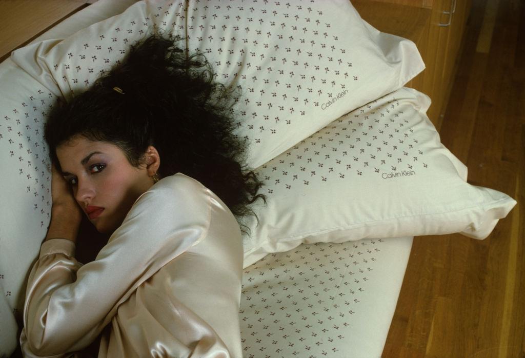 Janice Dickinson dressed in a silk gown, as she lies on a sofa, 1978.