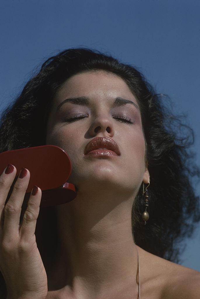 Janice Dickerson as she holds a make-up compact in one hand, Amagansett. New York, October 1978.