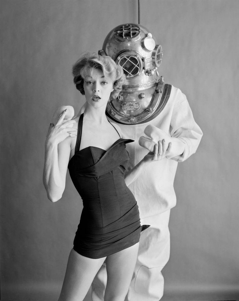 Jean Patchett poses in a swimsuit with a male model in an undersea diver's hardhat suit, 1950.